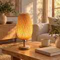 Lampe de table en bambou tressé allumée sur une table basse